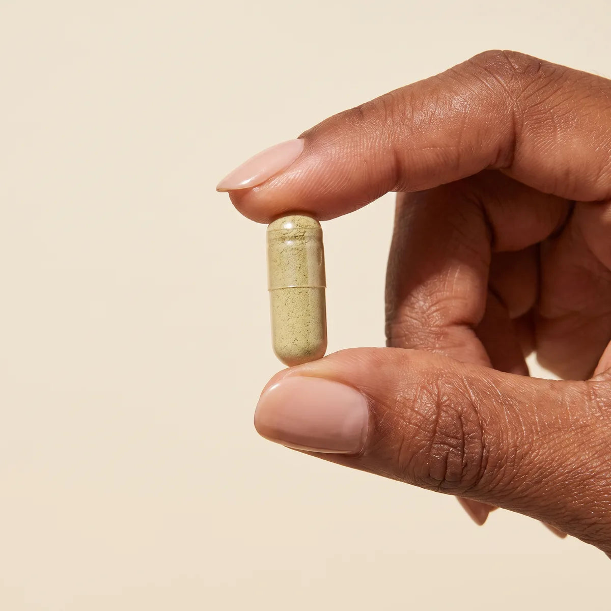 A Dandy extract capsule held between two fingers