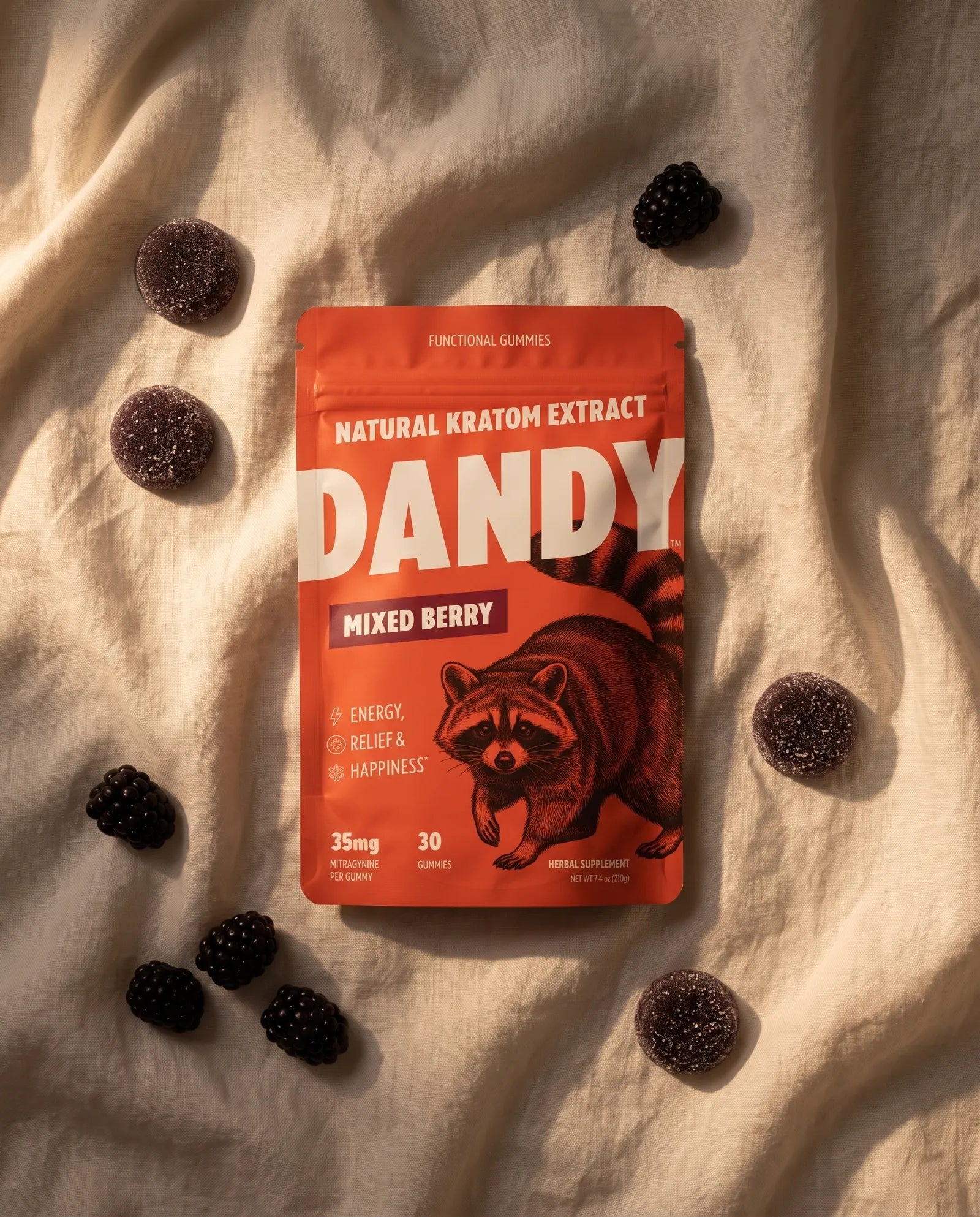 The Dandy pouch lying on cream linen with a few gummies and blackberries in warm evening light