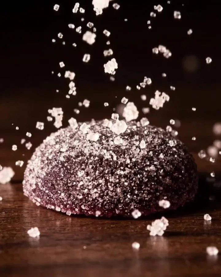 Coarse sugar crystals falling gently onto a Dandy Mixed Berry gummy and coming to rest