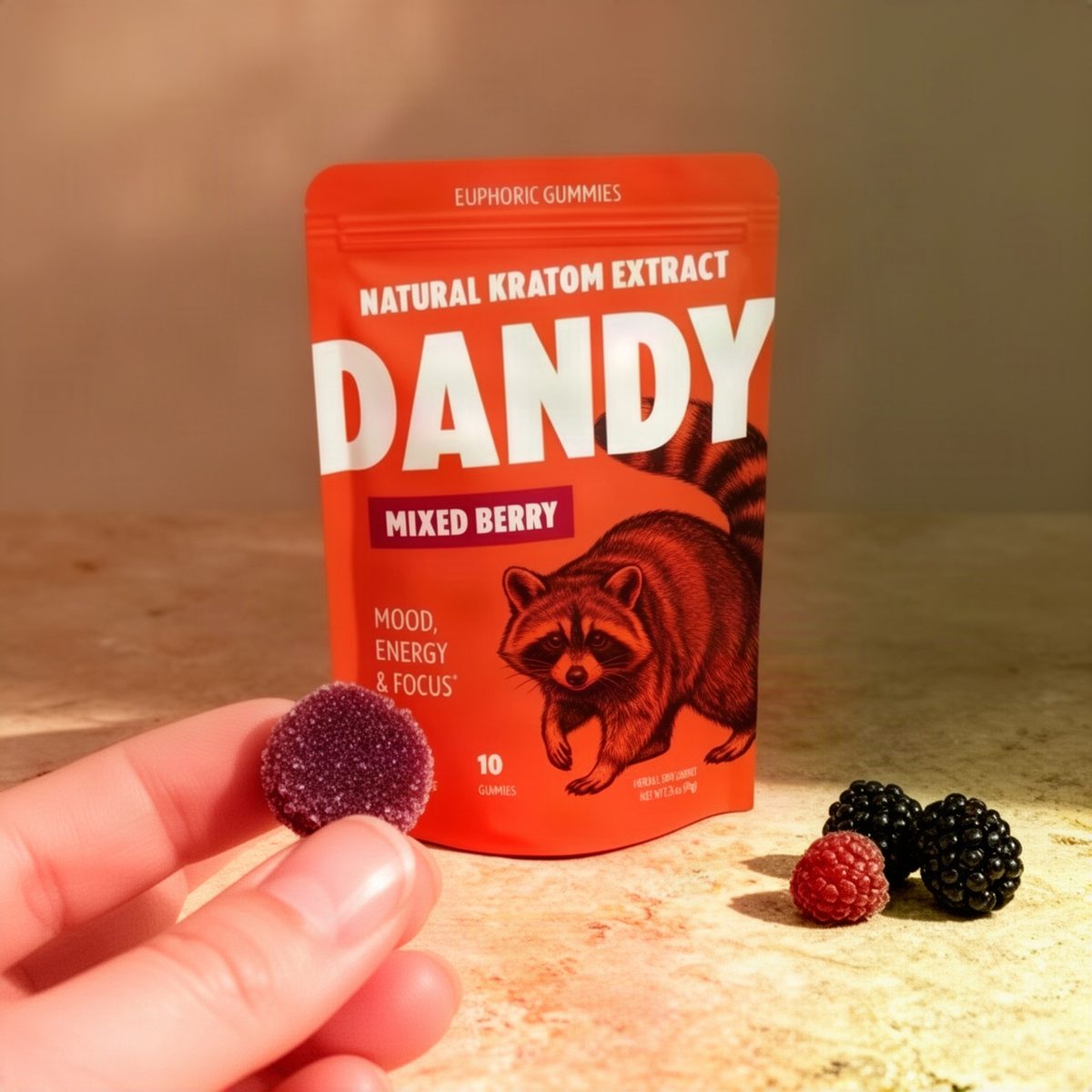 A Dandy Mixed Berry Gummies pouch on a counter with one small dark berry gummy held beside it for scale
