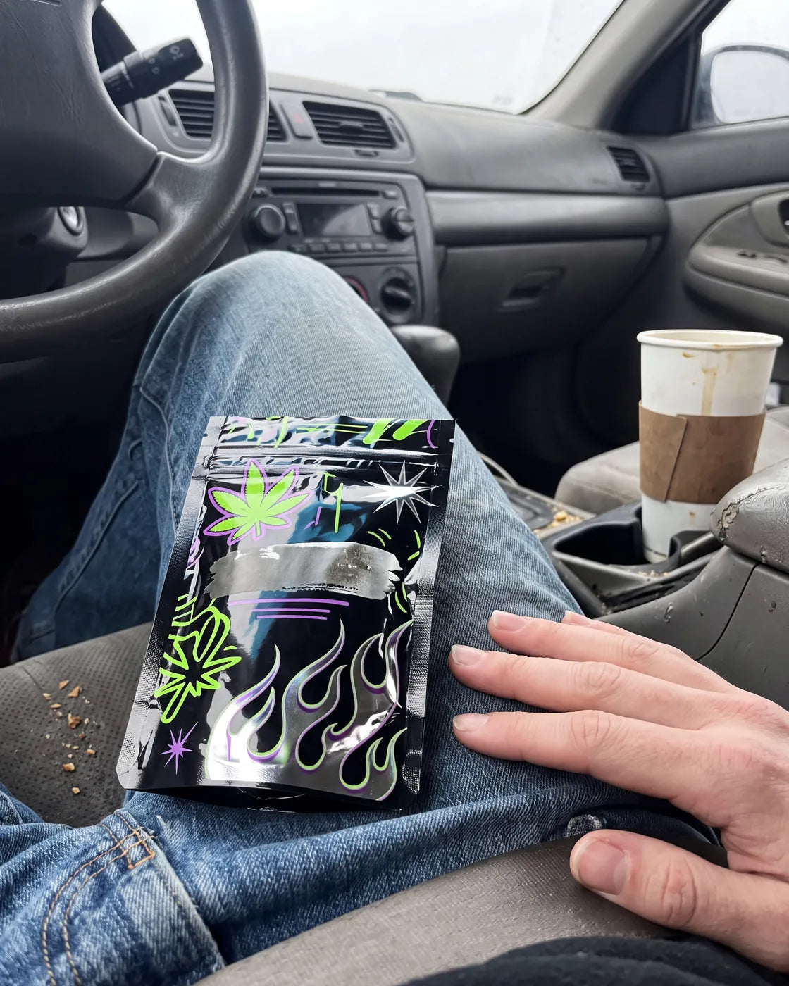 A loud unbranded kratom pouch resting on a lap in a parked car.