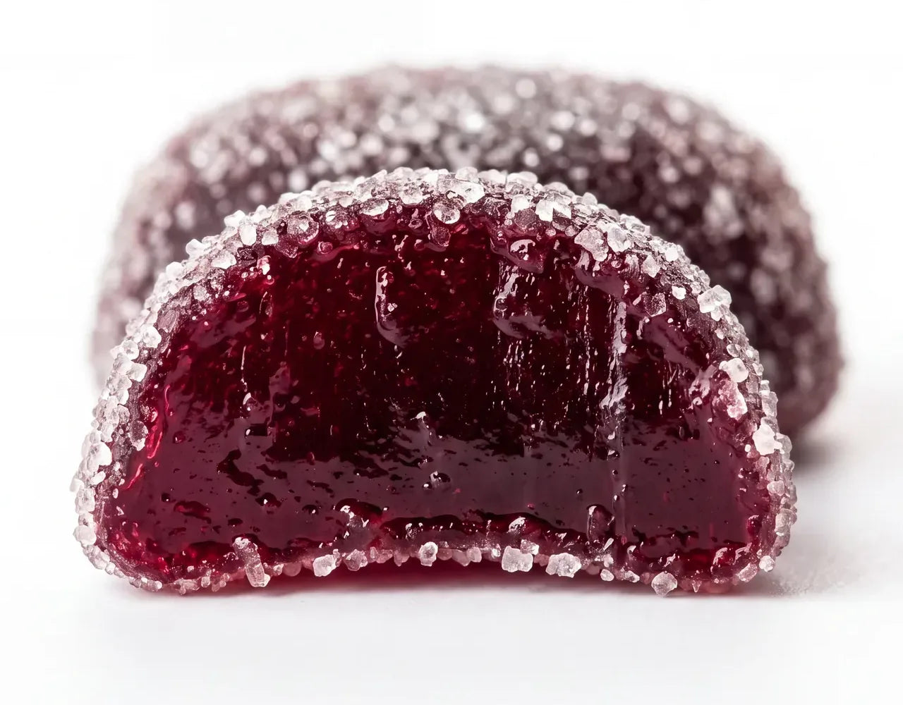 A Dandy mixed berry gummy bitten in half, glossy inside, with the pouch behind it.