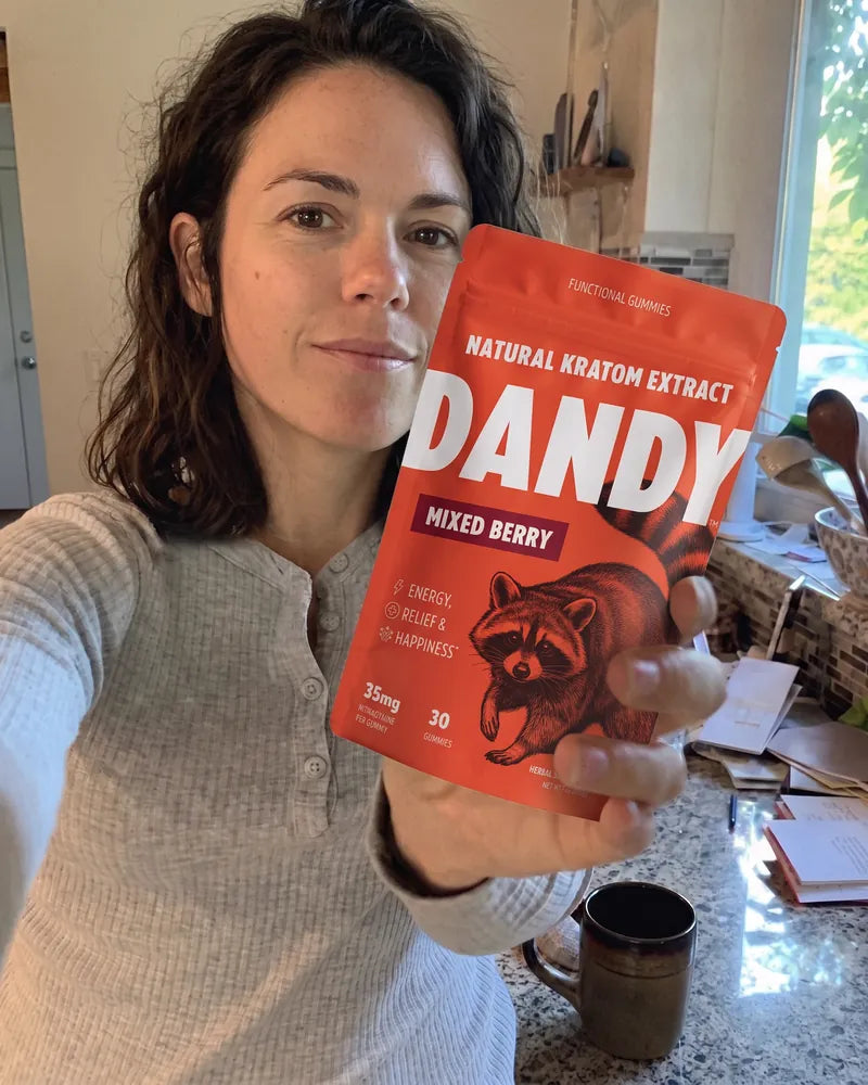 A customer holding up a Dandy mixed berry gummy pouch at their kitchen counter.