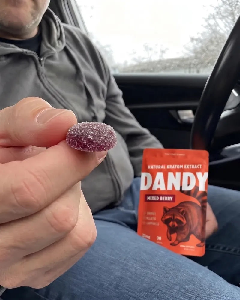 A customer in a parked car holding a single Dandy gummy up to the camera.